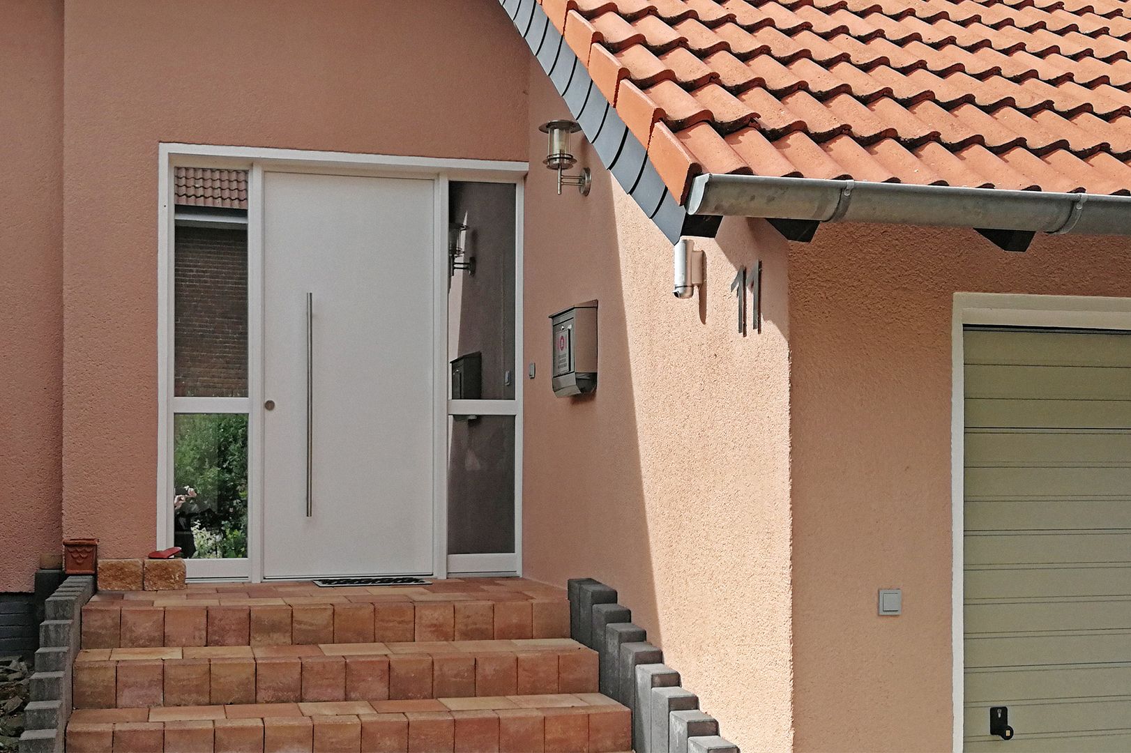 Terrakottafarbene Hausfassade mit weißer Tür