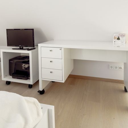 Weißer Schreibtisch mit Schubladen und einem Computermonitor auf einem TV-Ständer