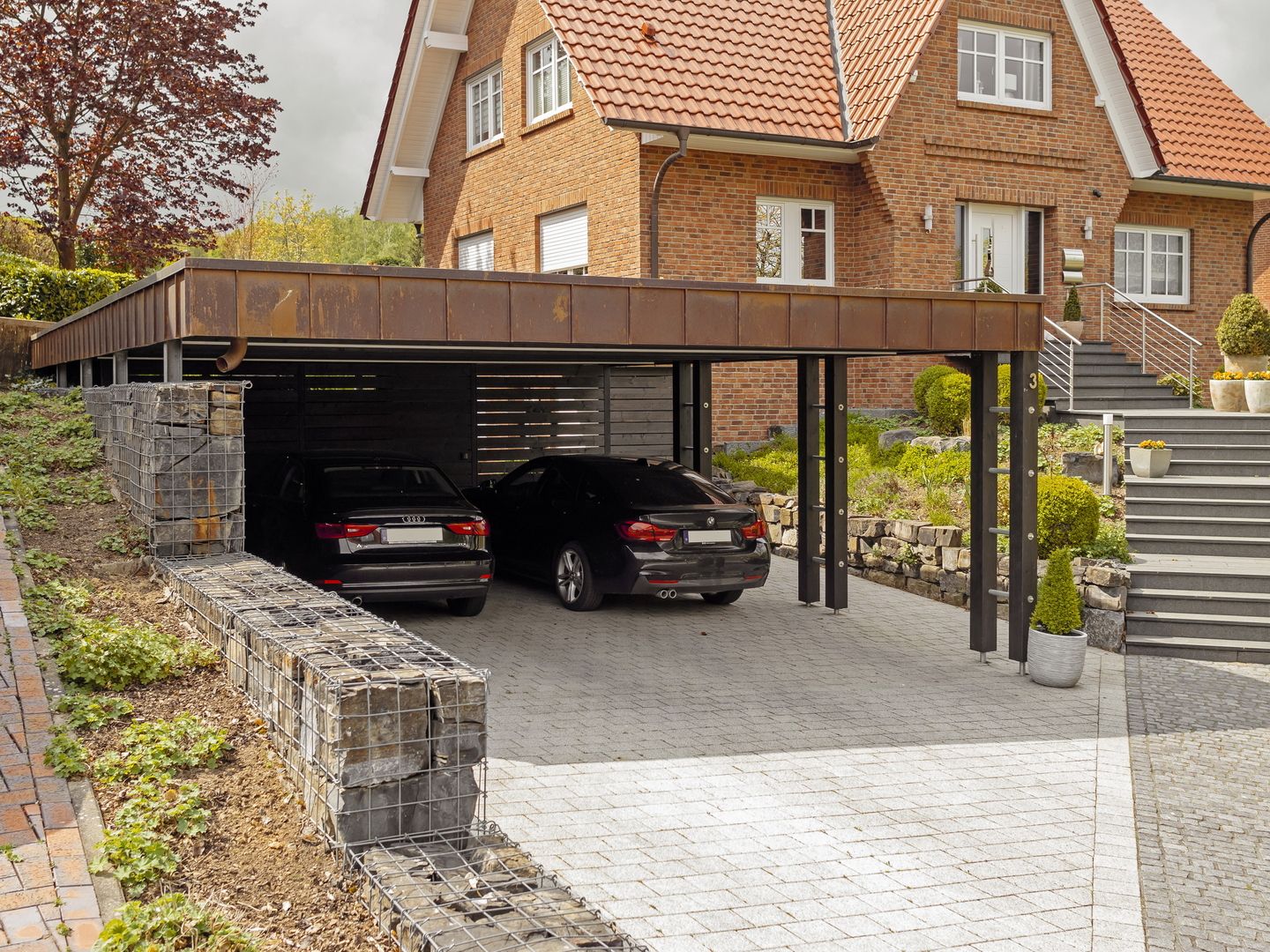 Carport mit zwei Autos unter dem Überhang eines Hauses